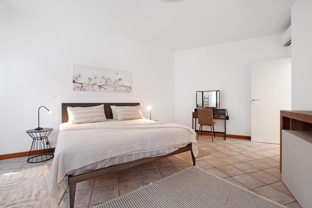 a white bedroom with a bed and a desk at Maddy's House in Mandello del Lario