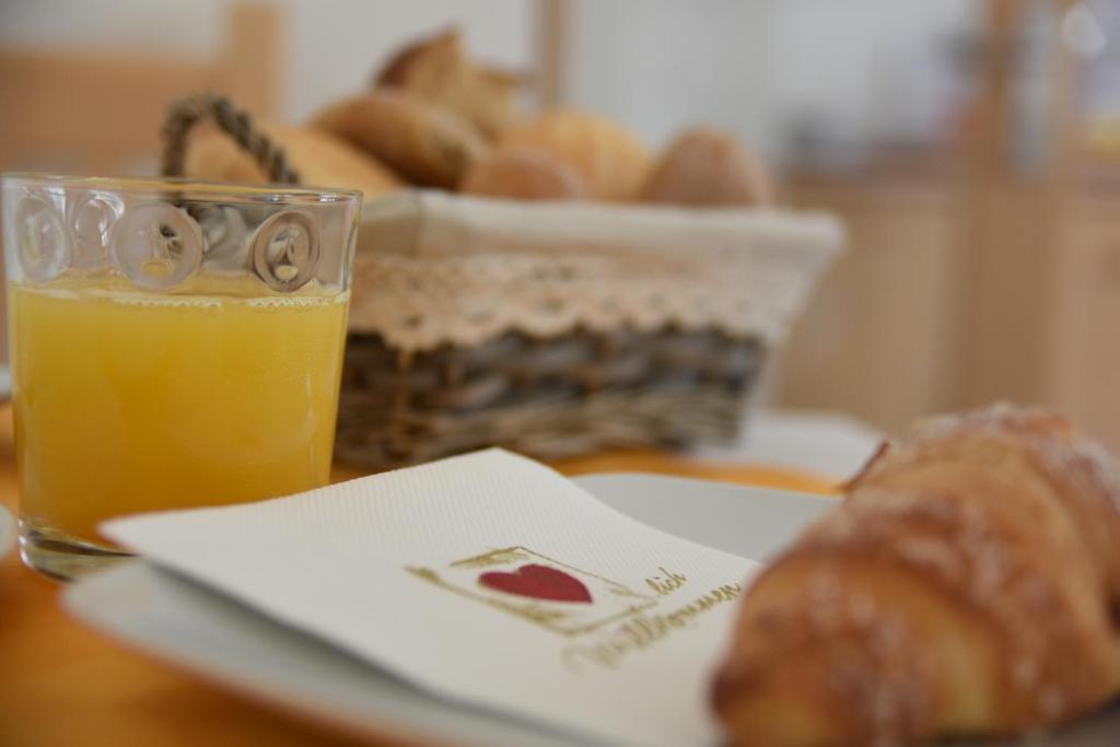a plate with a glass of orange juice and a basket of bread at B&B 3 Cuori in Predazzo