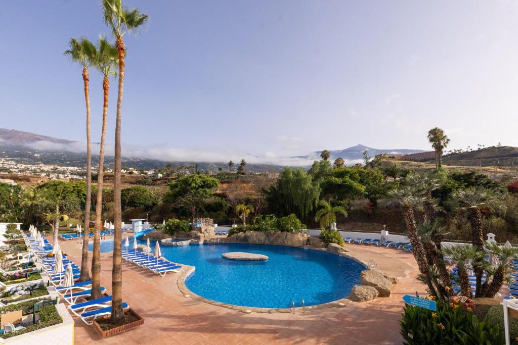 an empty pool with palm trees and lounge chairs at BLUESEA Costa Jardin & Spa in Puerto de la Cruz