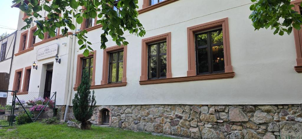 a building with windows and a stone wall at Zacisze Trzech Gór- klimatyczne noclegi i restauracja in Jedlina-Zdrój