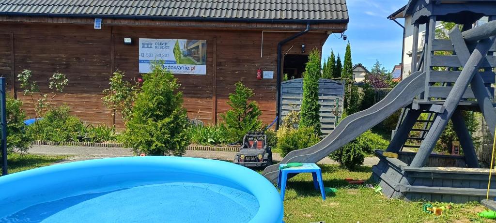 ein Spielplatz mit Rutsche im Garten in der Unterkunft Domki Olimp Resort Blisko Morza in Sarbinowo
