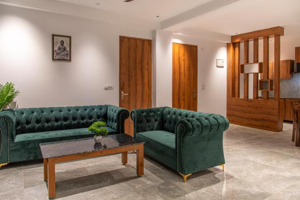a living room with two green couches and a table at The Royals Luxury Apartments Rooftop Restaurant Lift Live Music Sat in Kasauli