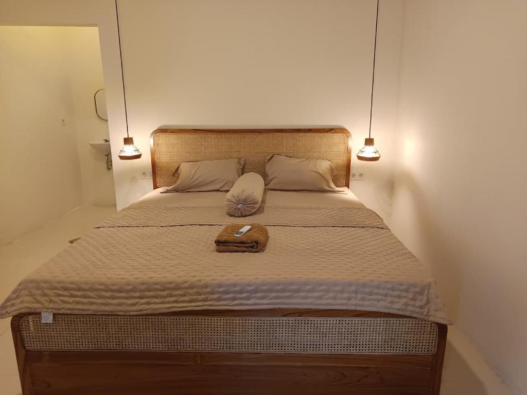 a bed with a wooden headboard with a book on it at AWAN Homestay in Kuta Lombok