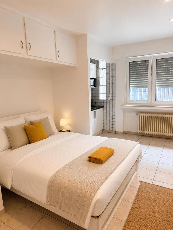 a bedroom with a large white bed with yellow pillows at Private Urban Studio 18 - Luxembourg Central in Luxembourg