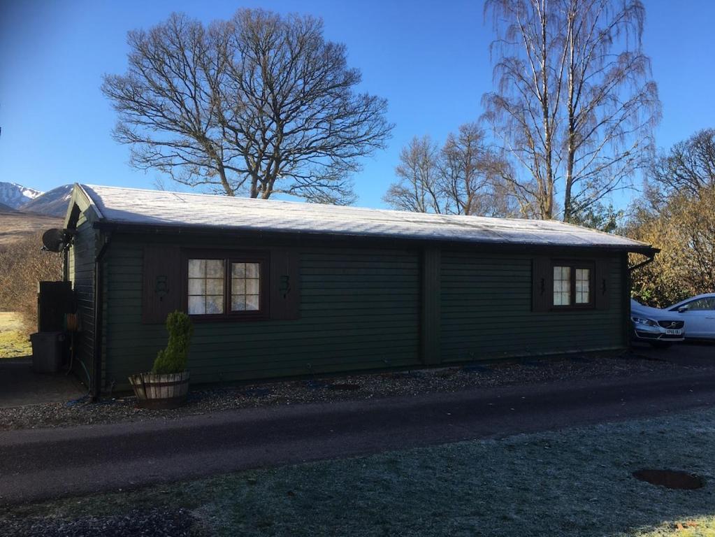 a green tiny house with a snow covered roof at Robins Nest in Roybridge