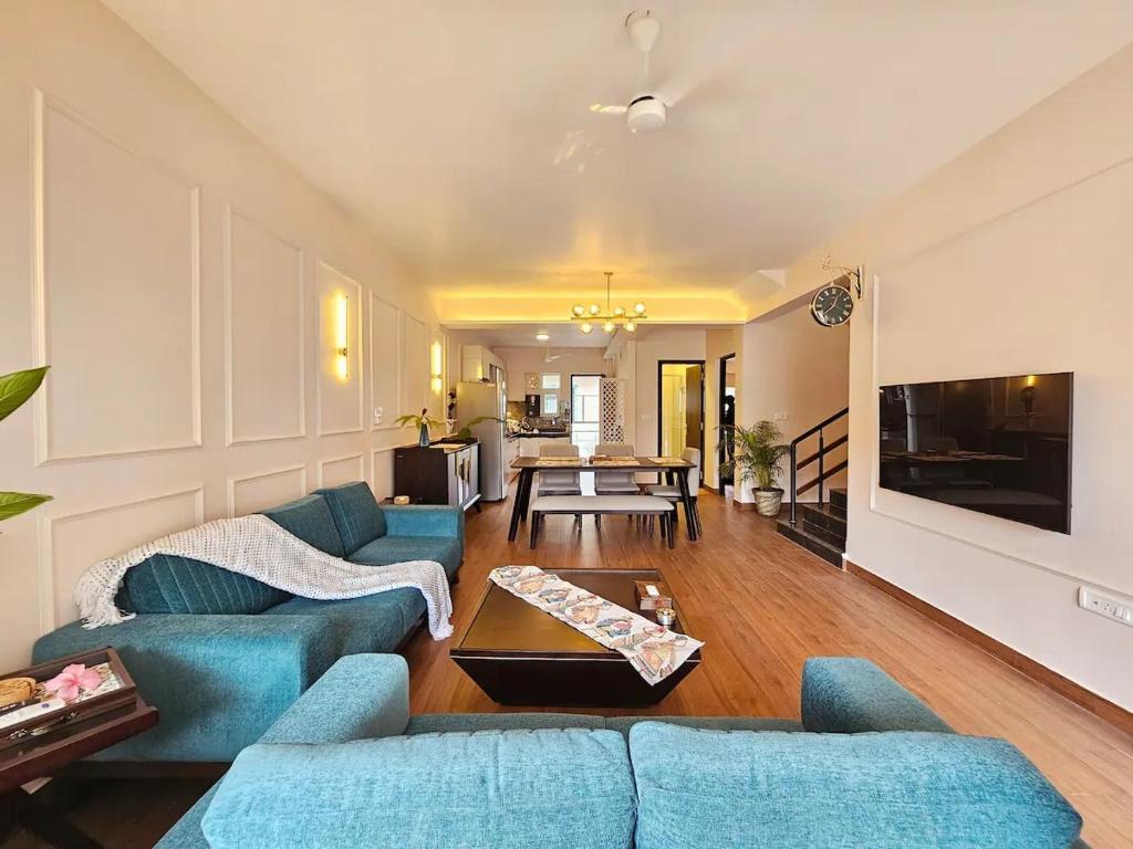 a living room with blue couches and a table at 3BHK Elegant Duplex Villa with Pool Access in Assagao