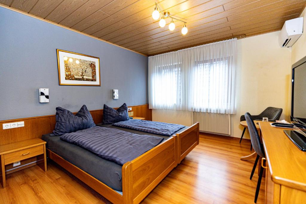 a bedroom with a bed and a desk and a computer at Hotel Garni KAMBEITZ in Ötigheim
