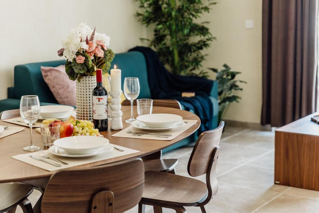 a dining room table with a vase of flowers and wine glasses at St Julians`s Boho Apartments in Is-Swieqi