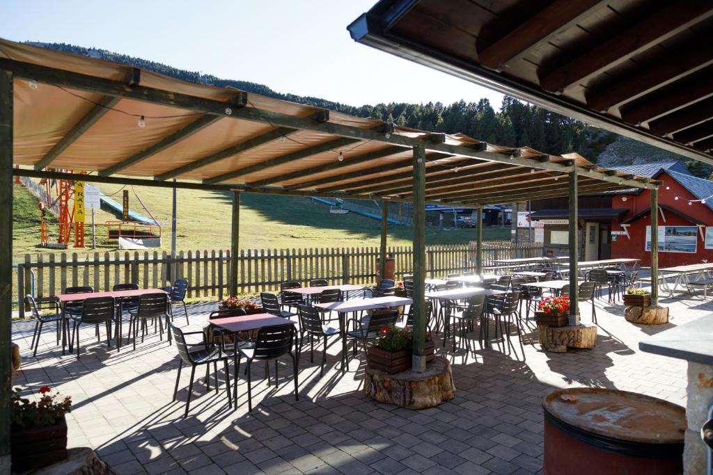 an outdoor patio with tables and chairs and a fence at Hotel Port 1730 in La Coma i la Pedra
