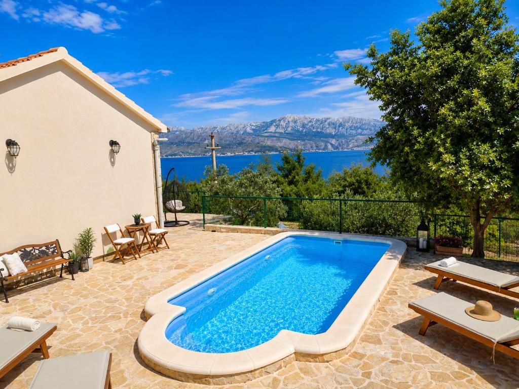 a pool in a backyard with a view of the water at Secluded Holiday home HERITAGE in Postira