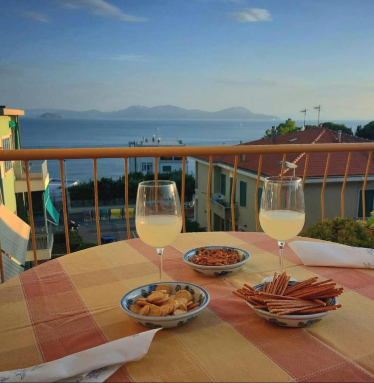 a table with two glasses of wine and snacks on a balcony at Il Balcone sull'Elba in Piombino