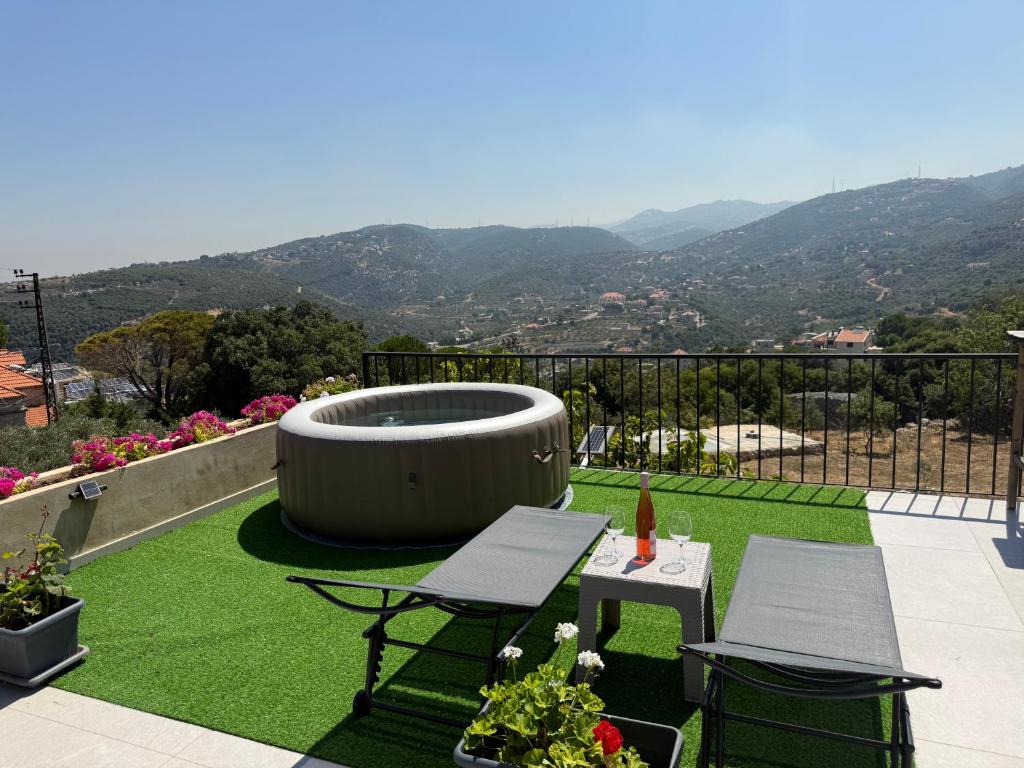 a patio with a hot tub and two chairs and grass at Beitkamle in Batroûn