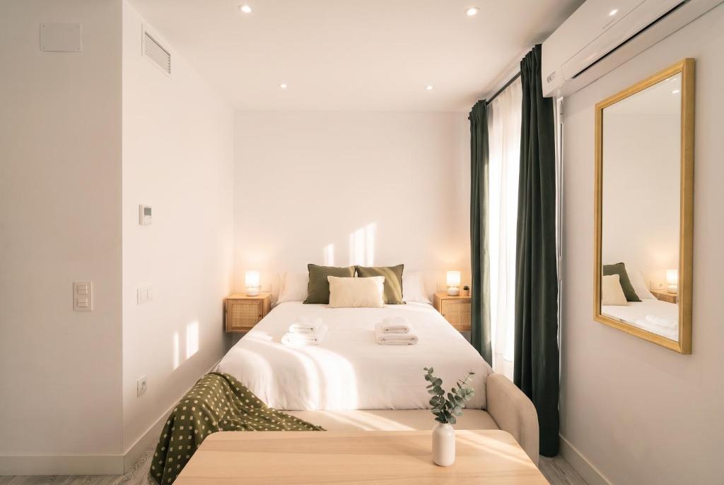 a white bedroom with a large bed and a mirror at InsideHome Ciudad del Cine in Valladolid