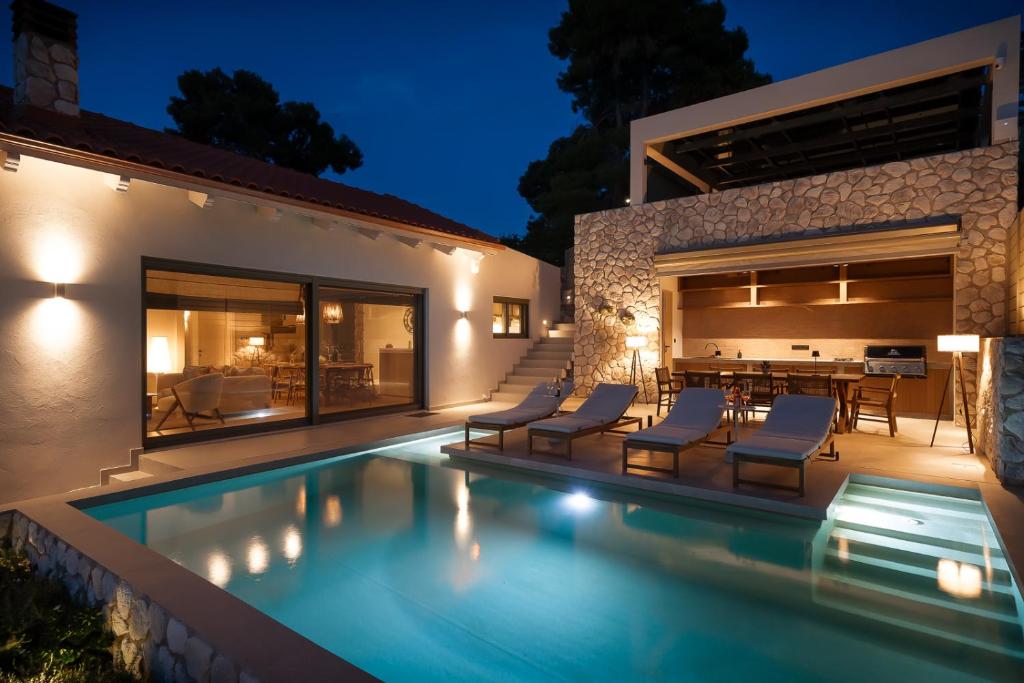 a swimming pool in the backyard of a house at night at Villa Carina by TwentyTwo in Ancient Epidauros