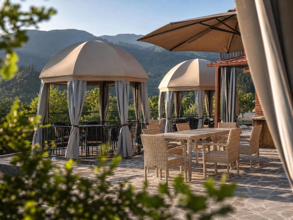 a patio with tables and chairs and an umbrella at Pesvebi Design Hotel and Cellar in Borjomi