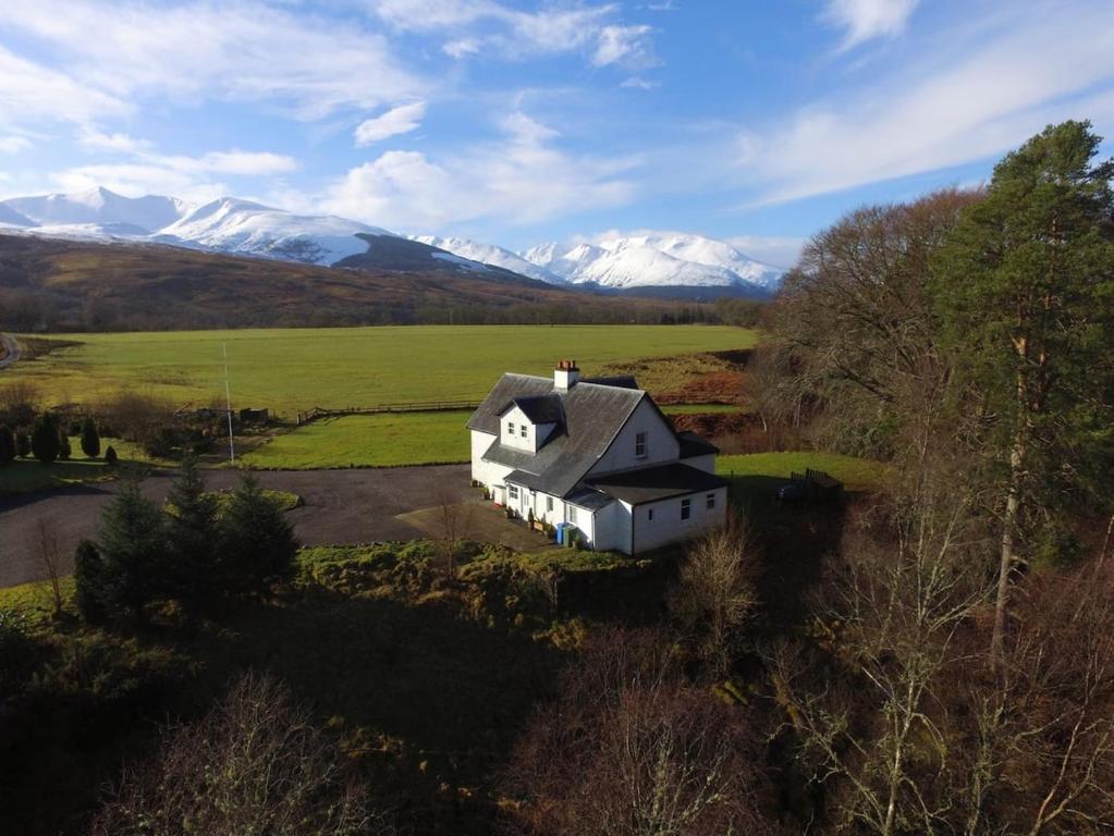 an aerial view of a house in a field with mountains at Farmhouse in Roybridge