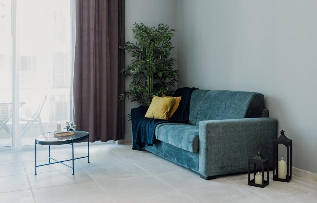 a living room with a blue couch and a potted plant at St Julians`s Urban Apartments in Is-Swieqi