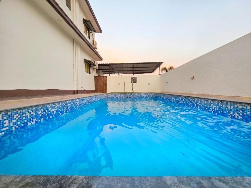 a swimming pool in front of a building at II EMPYREAN STAYS II WHITE PANTHER VILLA II 3BHK II AC II PRIVATE POOL ll in Lonavala