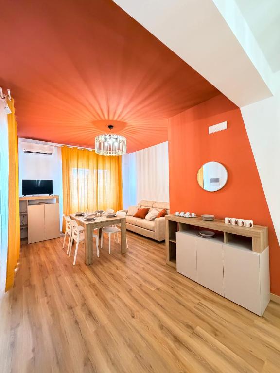 ein Wohnzimmer mit orangefarbenen Wänden und einem Tisch in der Unterkunft Cascina del colle - Casa Briè in Villamagna