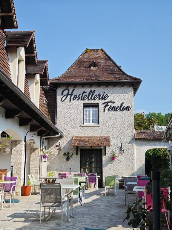 a restaurant with tables and chairs in front of a building at Le Fenelon in Carennac
