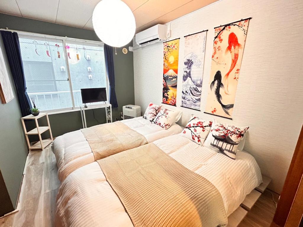 a bedroom with two beds and posters on the wall at サイプレス平岸 in Sapporo