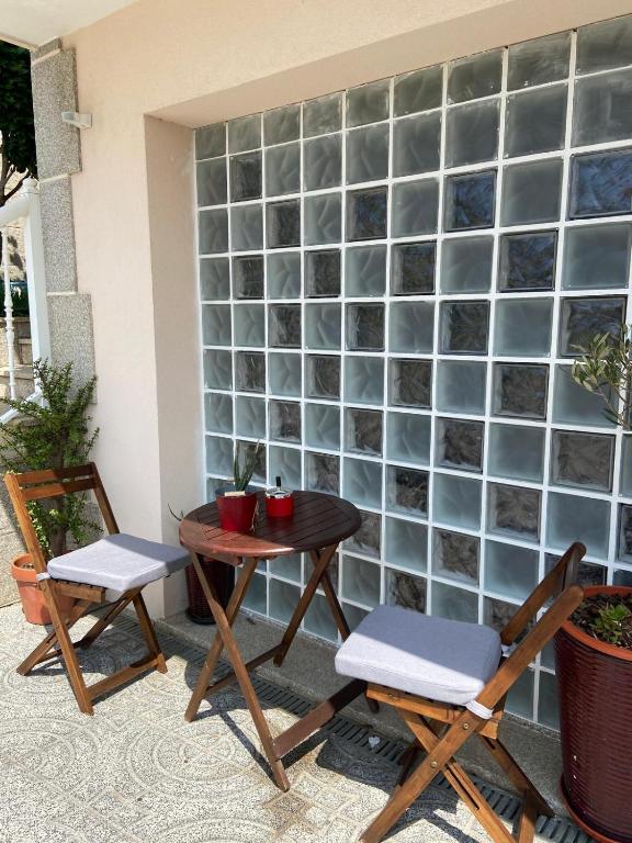 a patio with two chairs and a table and a wall at Maresia BIKE ROOMS in São Félix da Marinha