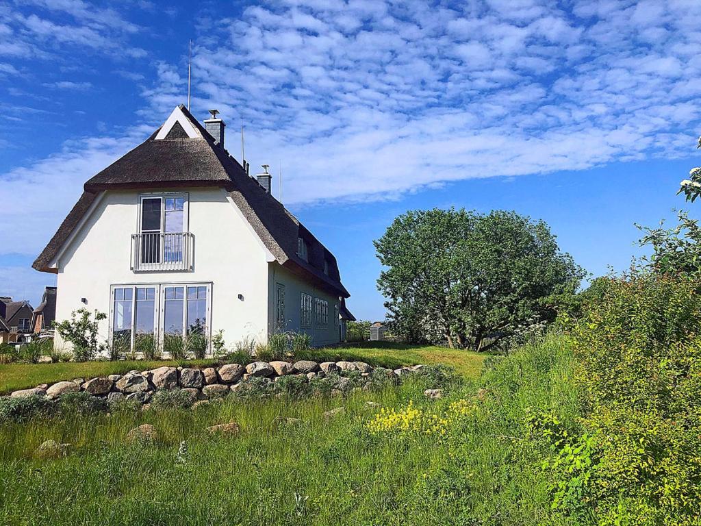 a white house with a black roof on a field at An der See in Dranske