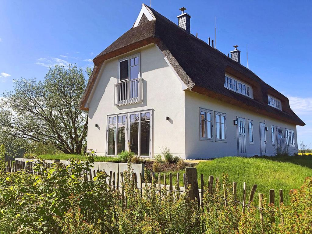 a white house with a gambrel roof on a hill at Auszeit am Meer in Dranske