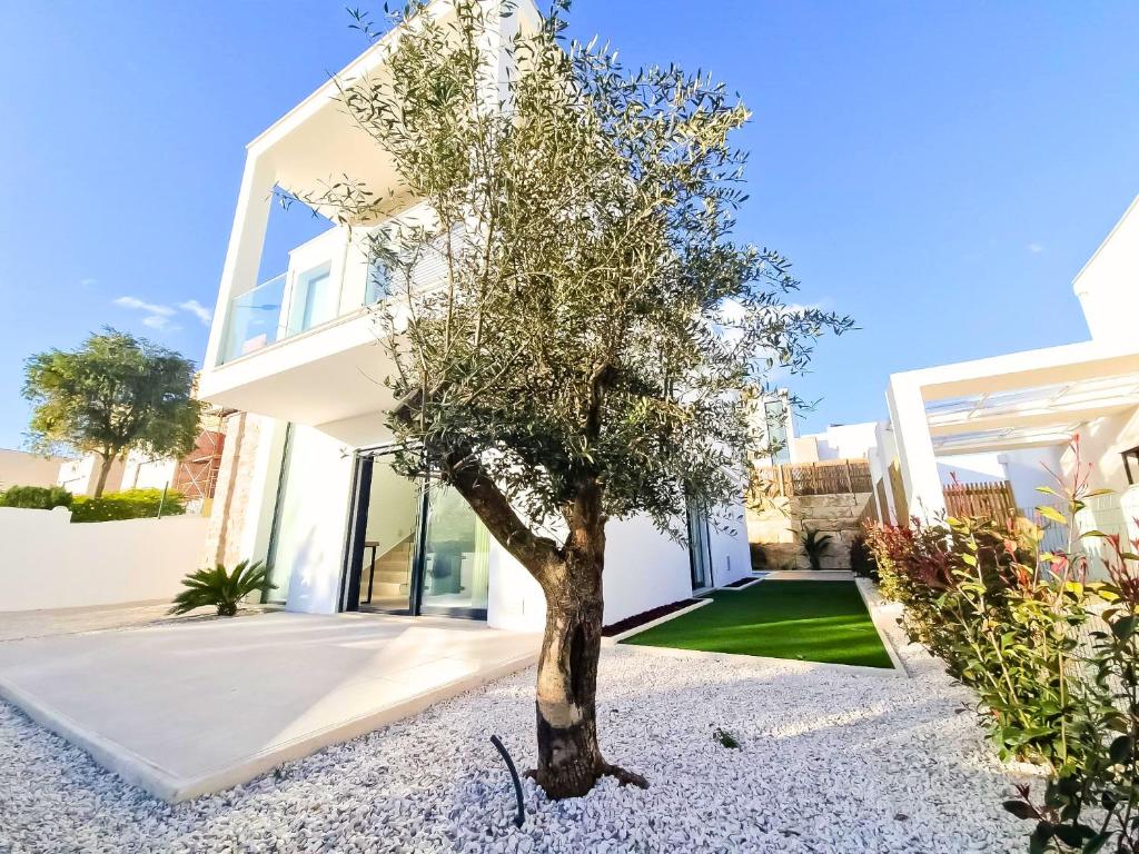 a white house with a tree in the front yard at Casa Encanto da Foz - BY SCH in Foz do Arelho