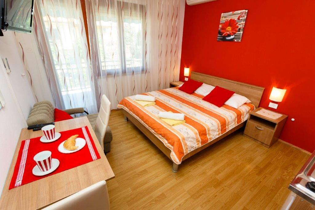 a red bedroom with a bed and a table at Studio 3 apartmani Braut in Kornić