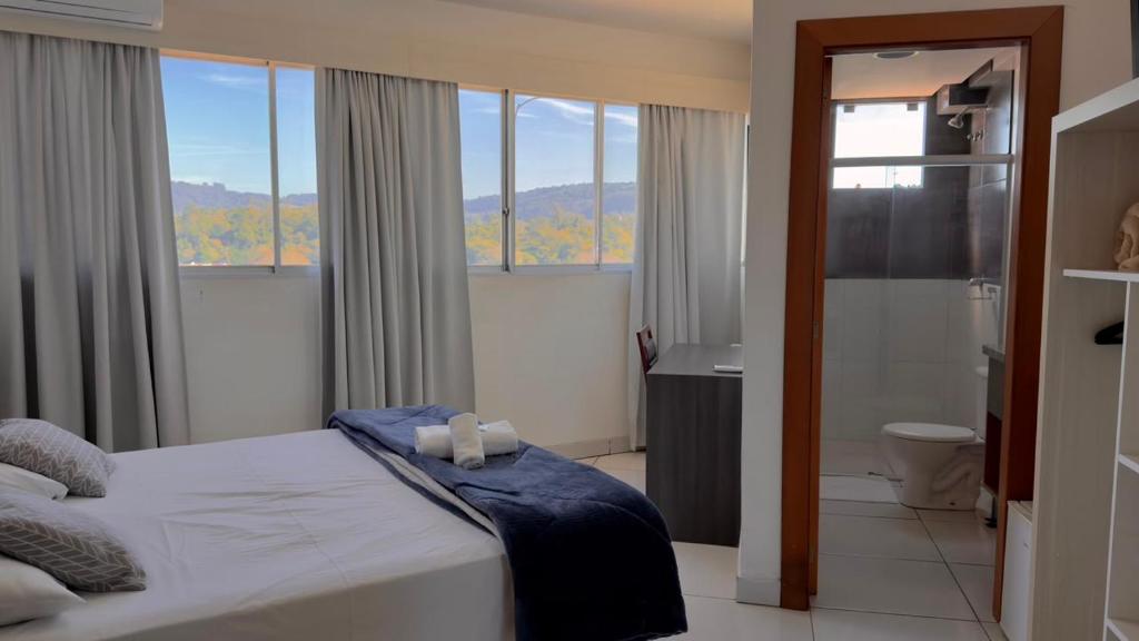 ein Schlafzimmer mit Bett und ein Badezimmer mit Fenstern in der Unterkunft Hotel Comoditá Ltda in Sapiranga