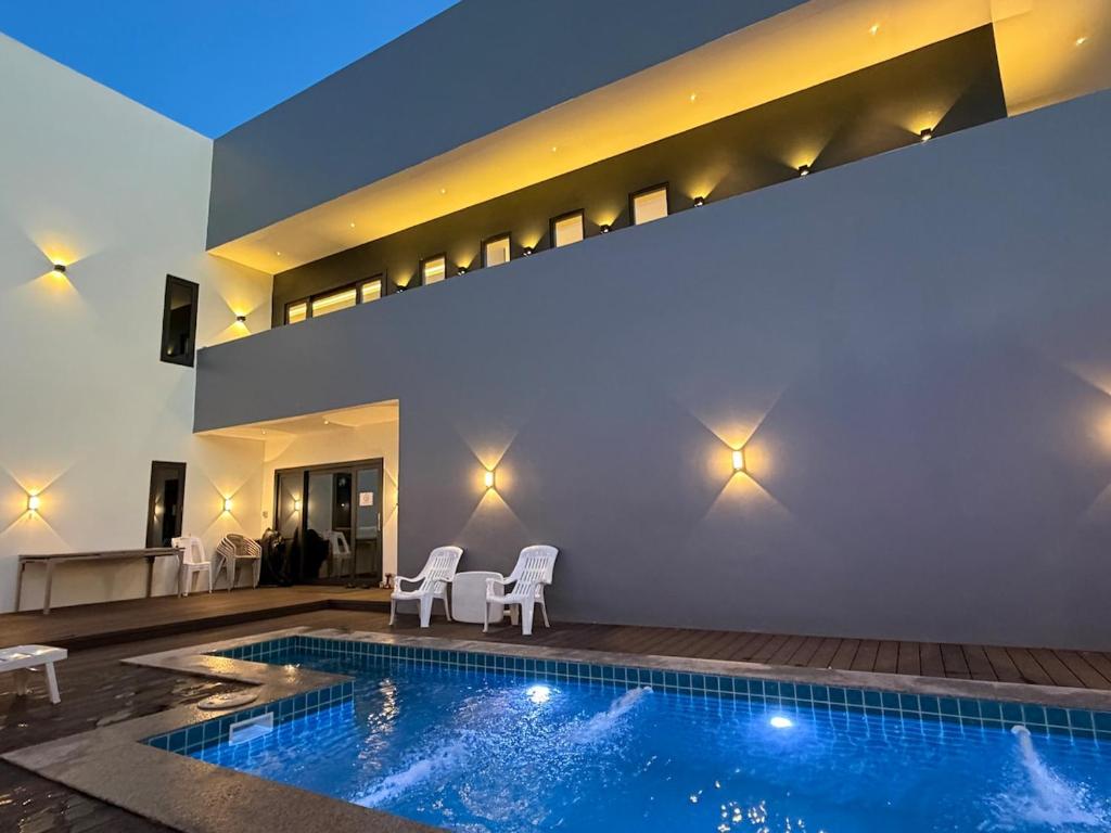 a swimming pool with two white chairs and a house at LaViena pool villa in Vientiane