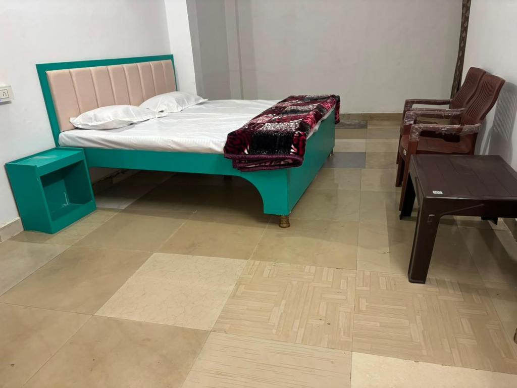 a bedroom with a bed and a chair and a table at Hotel RV in Jhānsi