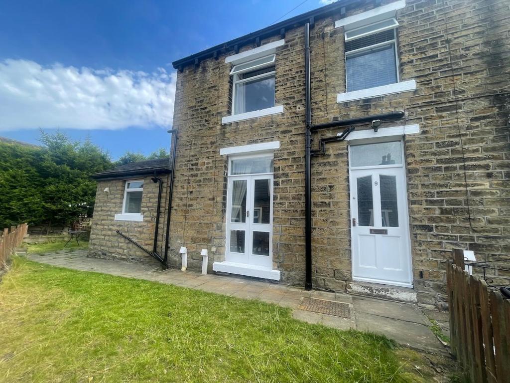 a brick house with a white door and a yard at Jagger Green Retreat in Greetland