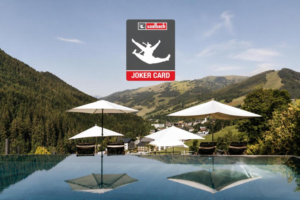 a swimming pool with umbrellas and a sign that reads lower grip at Hotel Thurnerhof in Saalbach-Hinterglemm