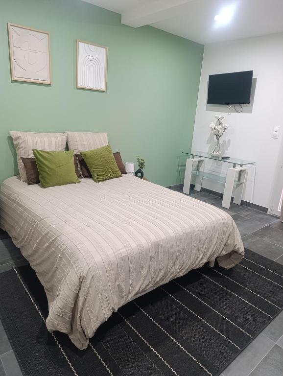 a bedroom with a large bed with green pillows at Studio Boulazac proche Palio in Boulazac