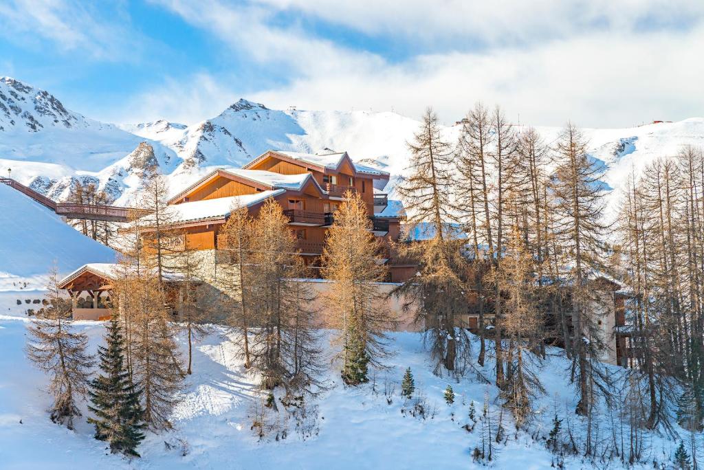 a house in the snow with mountains in the background at Lagrange Vacances Aspen in La Plagne
