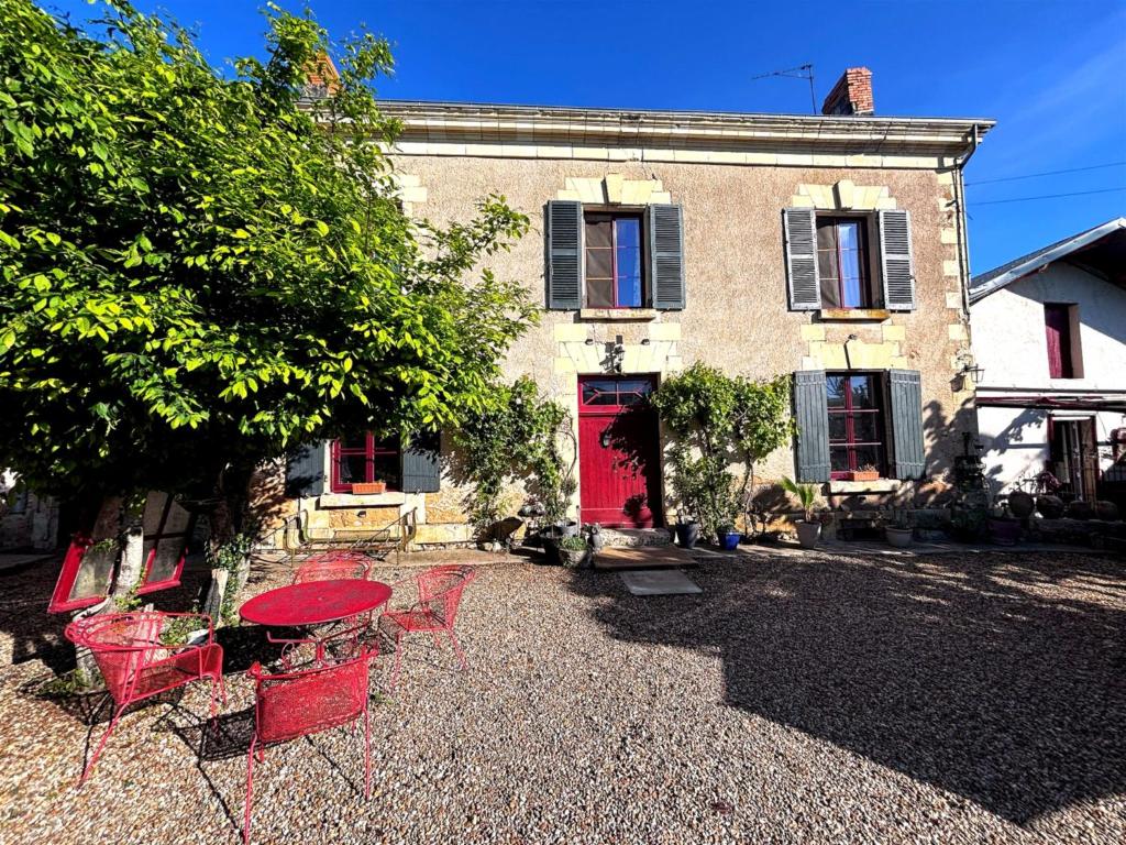 a red table and chairs in front of a building at Aux Caprices des Dieux in Marnes