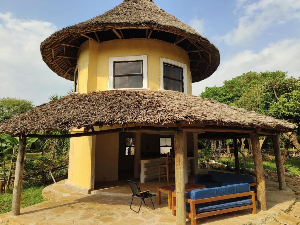a house with a thatched roof and a patio at Tiny house, kitchen downstairs in Shimoni