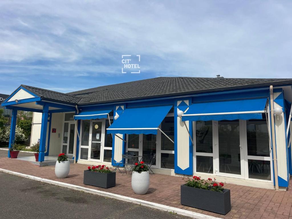 a blue building with flowers in front of it at Cit'Hôtel du Parc in Carrières-sous-Poissy