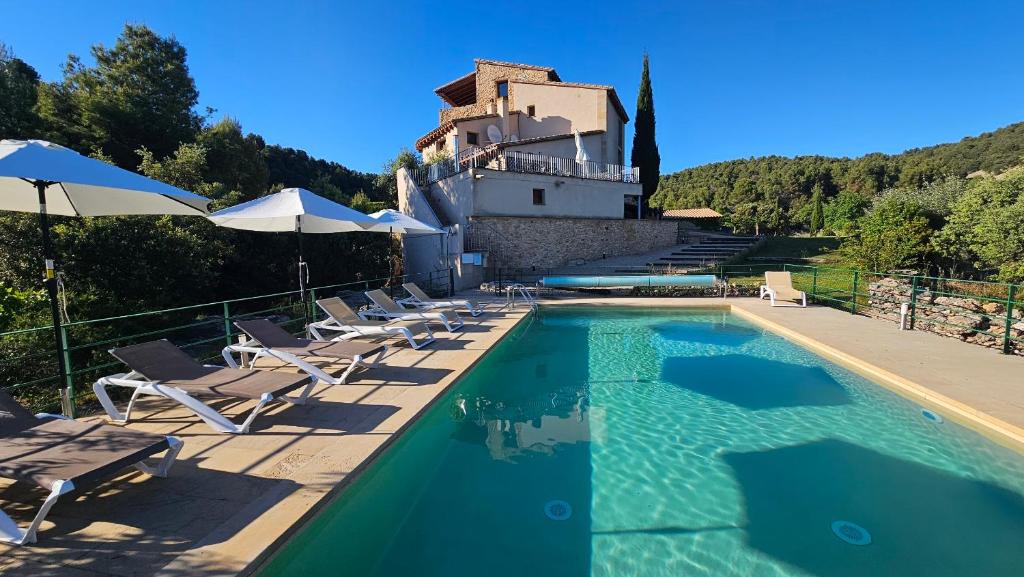 a swimming pool with chairs and a building in the background at Hotel Mas de la Serra in Fuentespalda