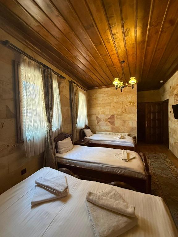 two beds in a room with a wooden ceiling at Akuzun Stone Hotel in Ürgüp