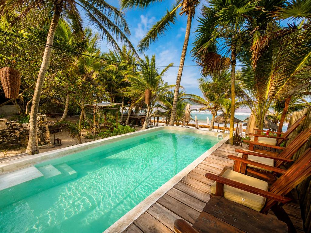 a swimming pool with chairs and palm trees at Dos Ceibas Tulum - Feel Good Hotel in Tulum