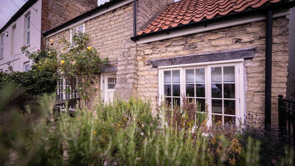 a stone house with a window and some tall grass at Freya's Cottage in Lincoln