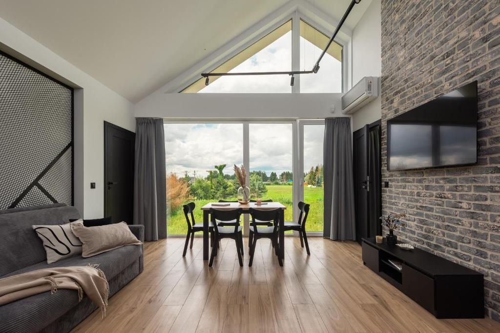 a living room with a table and chairs and a large window at Flatbook Stegna Południowa Apartamenty z Basenem in Stegna