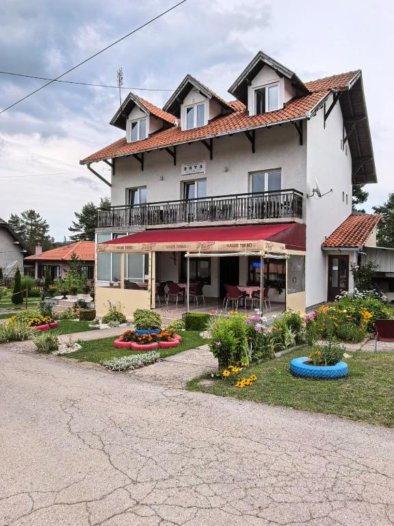 a large white house with a yard with flowers at Apartmani Vita in Divčibare