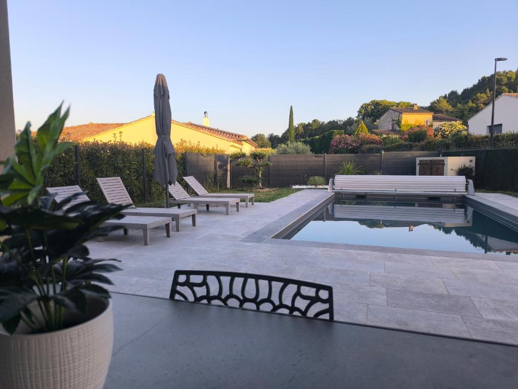 a pool with benches and an umbrella on a patio at villa récente climatisée avec piscine privée in Vaison-la-Romaine