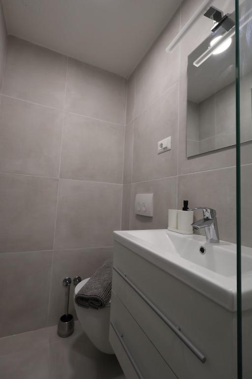 a white bathroom with a sink and a toilet at Downtown Condo w Huge TV in Zagreb