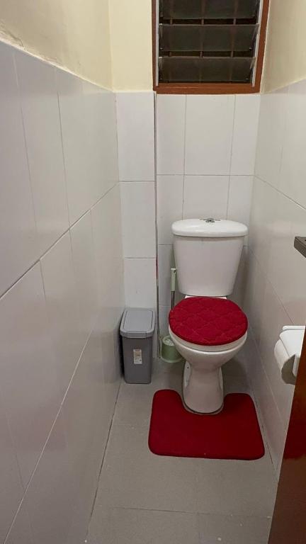 a bathroom with a toilet with a red seat at Affar homes in Kumasi