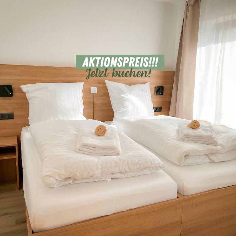 two beds with white sheets and pillows on them at Harmony - Schlafen im Stadtzentrum in Meiningen